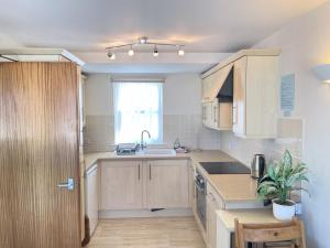 a kitchen with wooden cabinets and a sink and a window at 4 Crusoes - beachside apartment in St Ives