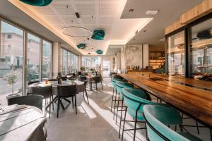 un ristorante con un lungo bar con sedie verdi di Hotel Rolly a Riva del Garda