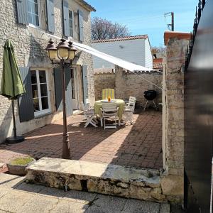 a patio with a table and chairs and a street light at Belle maison familiale près de La Rochelle in Ferrières