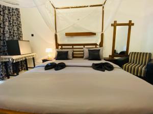 a bedroom with a large bed with two black shoes on it at Sigiri Holiday Bungalow in Sigiriya