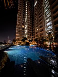 a large swimming pool at night with tall buildings at The Palladium - Executive Studio Pool-View in Iloilo City
