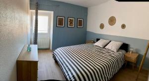 a bedroom with a bed with a striped comforter at Le Temps d'une Vendange in Lavigny