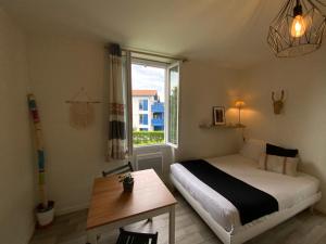 a bedroom with a bed and a table and a window at Studio lumineux & calme à Biarritz - Parking privé gratuit in Biarritz