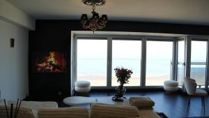 a living room with a table and chairs and windows at Frontal sea view apartment in Knokke-Heist