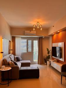 un soggiorno con un divano e una TV di Kate's Haven Jazz Residences Makati, Manila a Manila