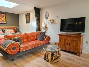 a living room with a couch and a flat screen tv at Vakantiestudio Huize Hout GR01 in Grijpskerke
