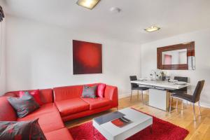 a living room with a red couch and a table at Stewards Cottage - North East Escapes in Bamburgh