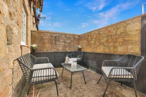 three chairs and a table on a patio at Stewards Cottage - North East Escapes in Bamburgh
