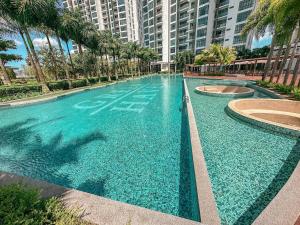 a large pool of blue water with palm trees and buildings at Starry B19 Green Haven 2BEDROOMS l NETFLIX in Masai
