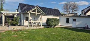 a white house with a table in a yard at Ferienhaus "Unter den Linden" in Eggesin