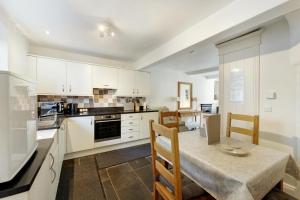 una cucina con mobili bianchi, tavolo e sedie di Pavement Cottage ad Ambleside