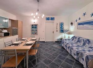 a kitchen and dining room with a table and a couch at Spiaggia a 5 Minuti, Giardino e Vista Mare - Due Splendide Villette Indipendenti in Palau
