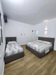two beds in a room with white walls and wooden floors at Villa Orange in Vlorë