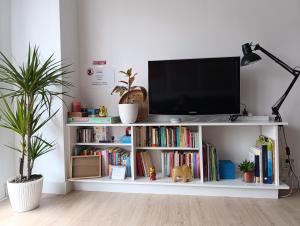 a tv on a white shelf with books at Apartamento 2 habitaciones cerca del puerto de Pasajes in Donostia-San Sebastián