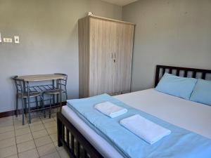 a bedroom with a bed with blue sheets and a table at Chill @ Phetchaburi in Phetchaburi