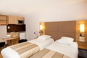 a hotel room with two beds and a kitchen at Séjours & Affaires Strasbourg Kleber in Strasbourg