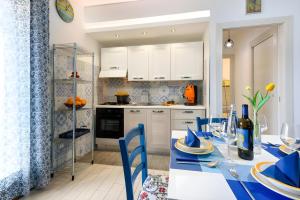 una cocina con una mesa con sillas azules y armarios blancos en Appartamento Dolceluna, en San Vito lo Capo