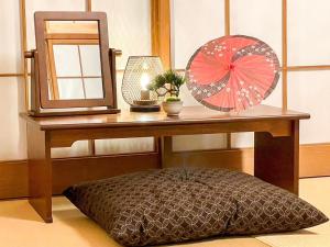 a dressing table with a mirror and a pink umbrella at Koco伊豆高原 in Ito