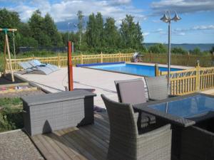 a wooden deck with chairs next to a swimming pool at RosaVillan in Kolmården