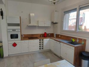 a kitchen with white cabinets and a sink and a window at Maison hyper centre à 3 minutes de cnpe in Gravelines