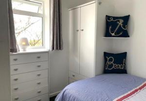ein Schlafzimmer mit einem Bett, einer Kommode und einem Fenster in der Unterkunft Primrose Valley Bungalow in Filey + 11 Fotos