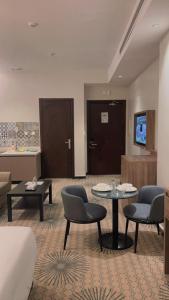 Una sala de estar con sillas y mesas en una habitación de hotel. en Glamour Inn AL Nuzha -جلامور ان النزهة, en Yeda