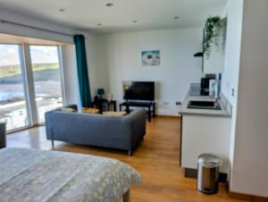 a living room with a couch and a kitchen at cellar cove in Perranporth