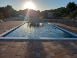 a swimming pool with the sun in the background at Relaxing Mobile Home Maestral - Beach, Private Jacuzzi, Pool Access in Drage
