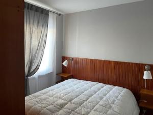 a bedroom with a white bed and a window at Villa Istria Apartment in San Vito di Cadore