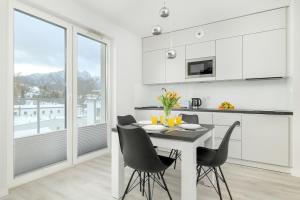 扎科帕内Comfortable Apartments in the Centre of Zakopane with Parking, SPA & Gym by Noclegi Renters的配有白色橱柜、桌子和椅子的厨房