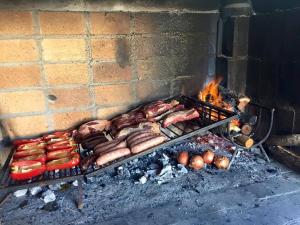 a grill with a bunch of meat and hot dogs at Montevideo Chic Hostel in Montevideo