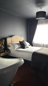 1 dormitorio con cama y bañera junto a una ventana en The Hideaway, en Mánchester
