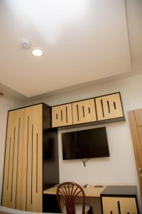 a kitchen with wooden cabinets and a desk with a tv at Saphir Boutique Hotel in Kigali