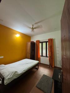 a bedroom with a bed and a yellow wall at Krishnalayam Heritage Villa in Elimala
