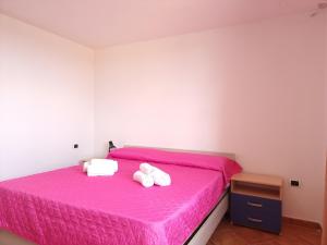 a bedroom with a pink bed with towels on it at Residenze Pedrame in Budoni