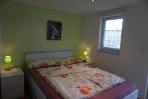 a bed in a bedroom with two lamps and a window at Ferienwohnung Am alten Holzweg in Endlichhofen