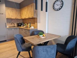 a kitchen with a wooden table and chairs and a clock at Apartament Moja Magdalenka in Zarzecze