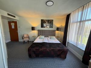 a bedroom with a large bed and a chair at Het Rechthuis in Uithoorn