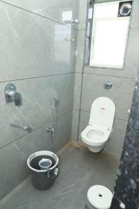 a bathroom with a toilet and a shower and a bucket at Hotel Rajmahal Palace Bhimashankar pune in Taleghar