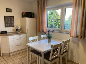 a kitchen with a white table and chairs and a window at Sonnenstern Lemkenhafen in Fehmarn