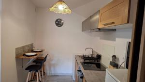 a kitchen with two bar stools and a clock on the wall at La petite Brézègue in Aguessac
