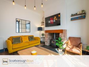 a living room with a yellow couch and a fireplace at Scarborough Stays - Darcey House in Scarborough