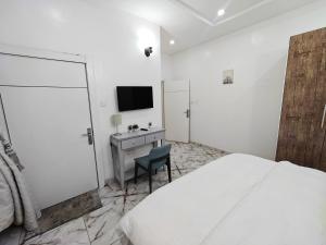 a bedroom with a bed and a desk and a television at Eko City Apartment - 24hrs Power, Security, Wifi, Netflix, Fully Equipped Kitchen in Lekki