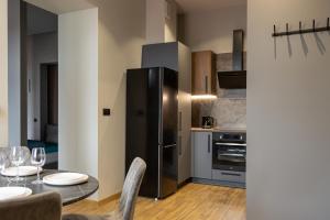 cocina con nevera negra y mesa con sillas en The 9 Apartments, en Przemyśl