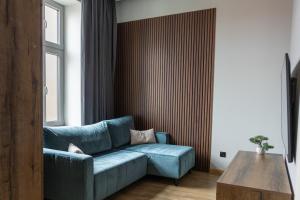 Una sala de estar con un sofá azul y una mesa. en The 9 Apartments, en Przemyśl