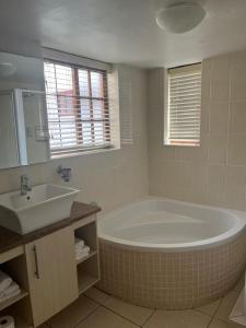 a bathroom with a large tub and a sink at At Sta-Plus Guest House in Port Elizabeth +21 photos