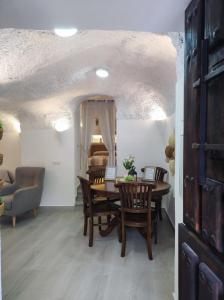 a dining room with a table and chairs and a bedroom at Cueva Virgen de las Nieves in Monachil