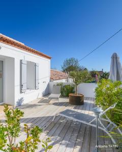 a patio with a chair and an umbrella on a house at Barbâtre Les Figuiers Plage à 500 m in Barbâtre