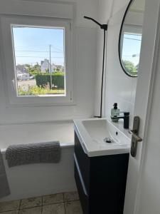 ein Badezimmer mit Waschbecken und Fenster in der Unterkunft Maison de charme 3 chambres plage de Lodonnec in Loctudy