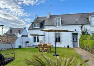 ein Haus mit einem Tisch und einem Sonnenschirm im Hof in der Unterkunft Maison de charme 3 chambres plage de Lodonnec in Loctudy